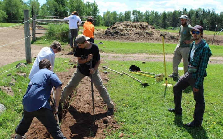 A group of young people use gardening tools during a service project with outward bound. 